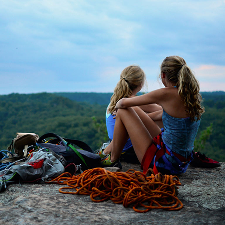 two rock climbers sitting next to a pile of climbing rope