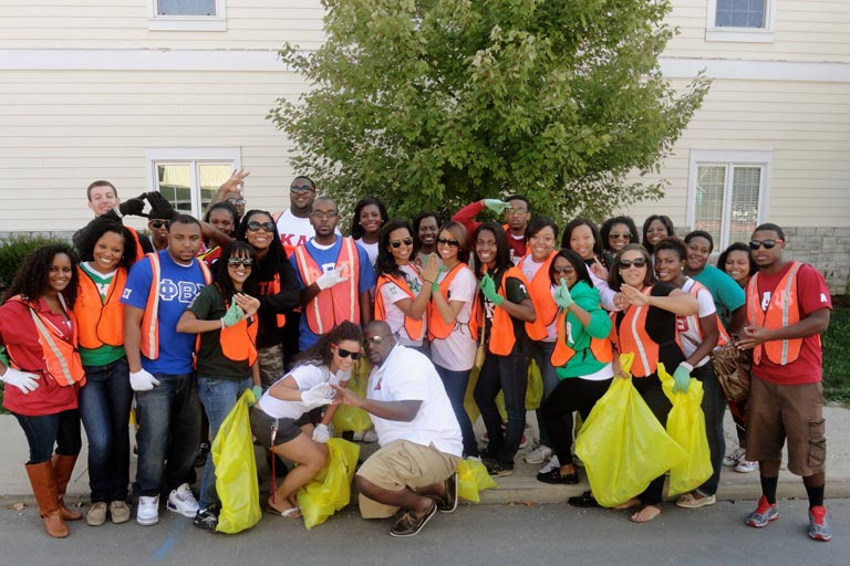 members of the national Panhellenic council, wearing bright orange vests and holding yellow trash bags