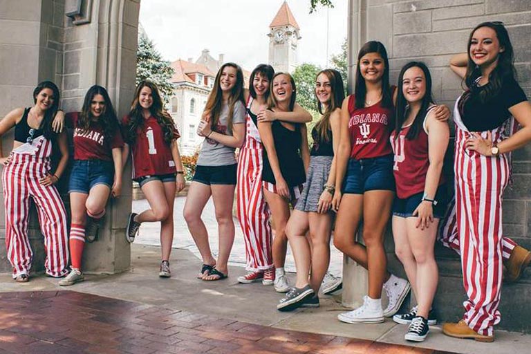 several members of the Panhellenic association wearing red and white striped bib overalls