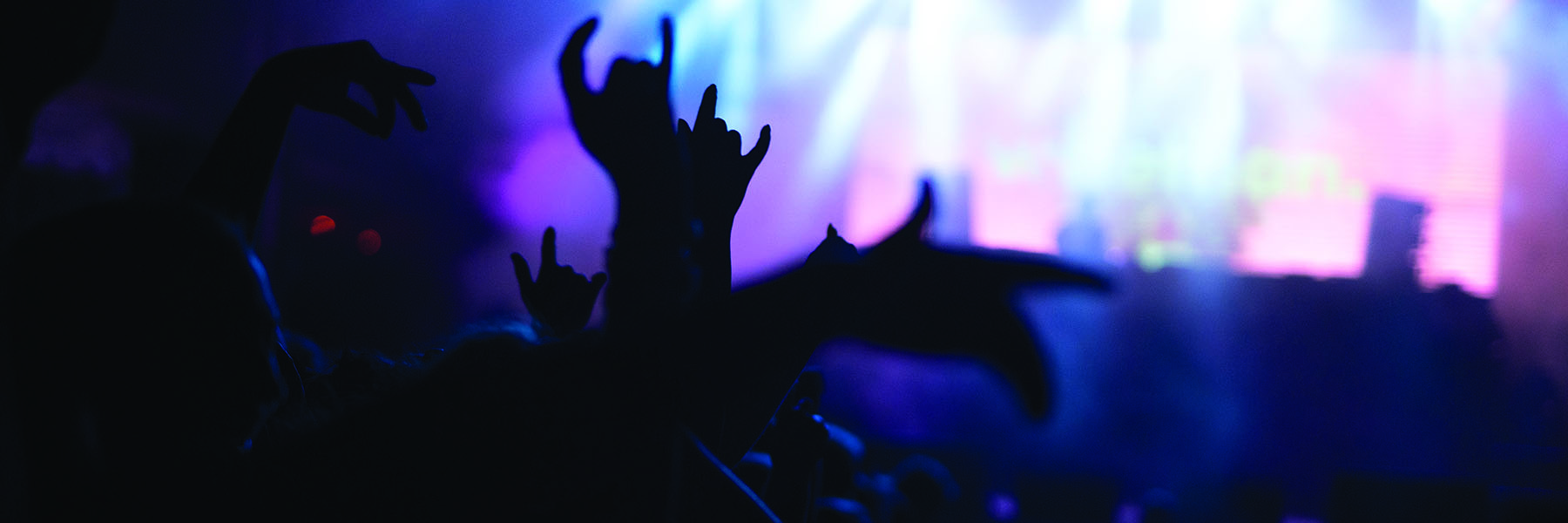 silhouetted hands raised at a concert